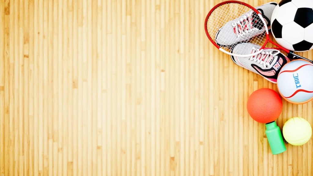 A vibrant flat lay of sports equipment for children, including a soccer ball, tennis racket, running shoes, and a water bottle, all arranged on a wooden gym floor.